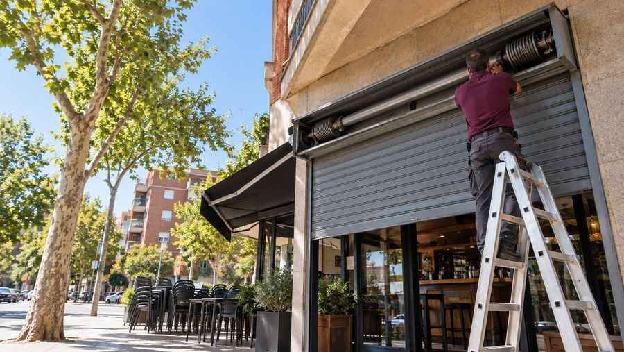 Técnico revisando la ballesta y el eje de un cierre metálico de lama ciega a medio subir